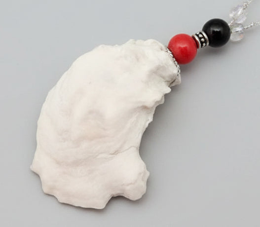 White shell pendant with dark pink and black beads on white background